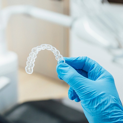 Dentist holding clear aligner with blue glove