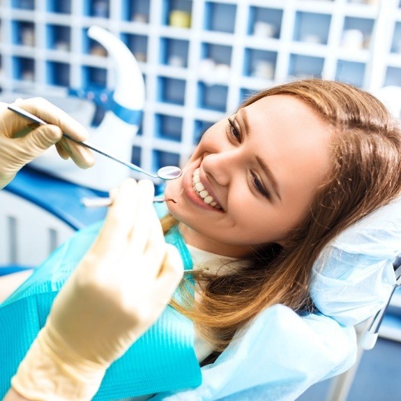 Smiling woman receiving preventive dentistry checkup and teeth cleaning