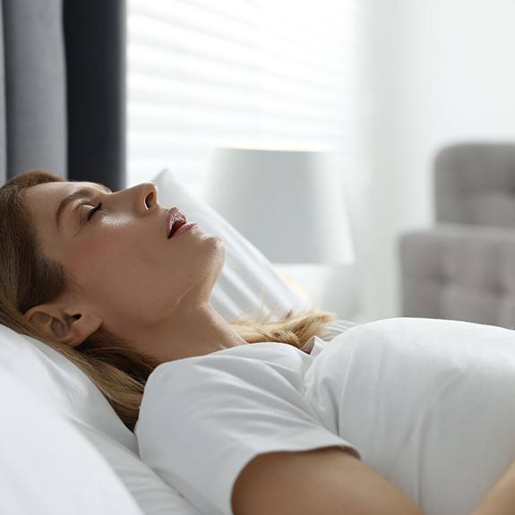 Woman in white shirt lying in bed