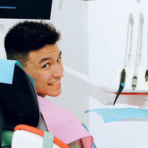 Smiling man in dentist’s chair looking over his shoulder