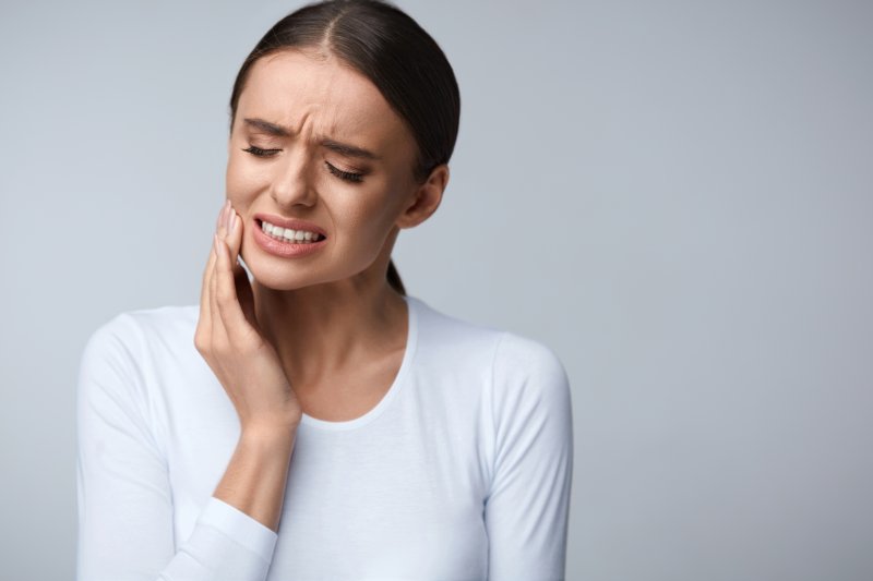 person with tooth sensitivity holding their cheek